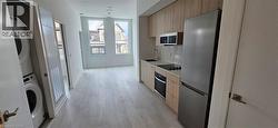 Kitchen featuring backsplash, stainless steel appliances, sink, light hardwood / wood-style floors, and stacked washer / drying machine -