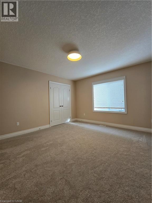 Spare room with light colored carpet and a textured ceiling - 93 Tremaine Drive, Kitchener, ON - Indoor Photo Showing Other Room
