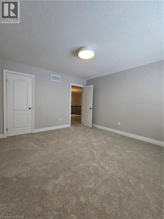 Unfurnished bedroom featuring carpet and a textured ceiling - 93 Tremaine Drive, Kitchener, ON - Indoor Photo Showing Other Room