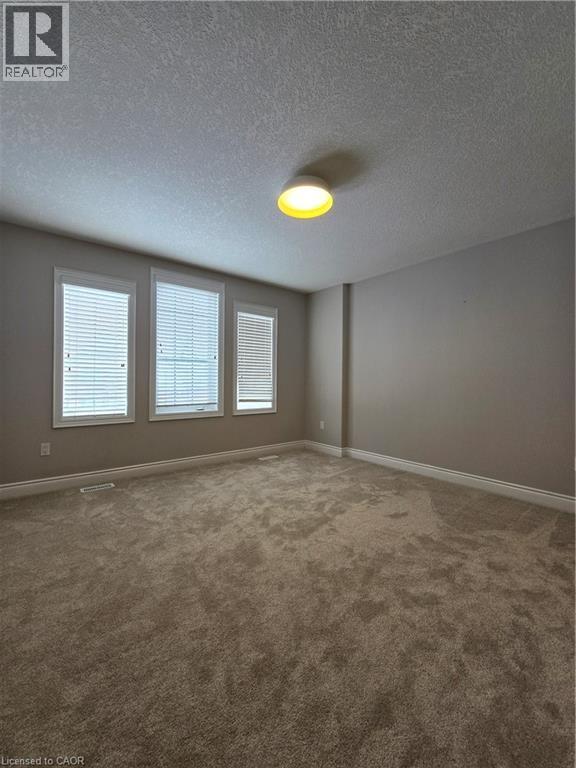 Carpeted empty room with plenty of natural light and a textured ceiling - 93 Tremaine Drive, Kitchener, ON - Indoor Photo Showing Other Room