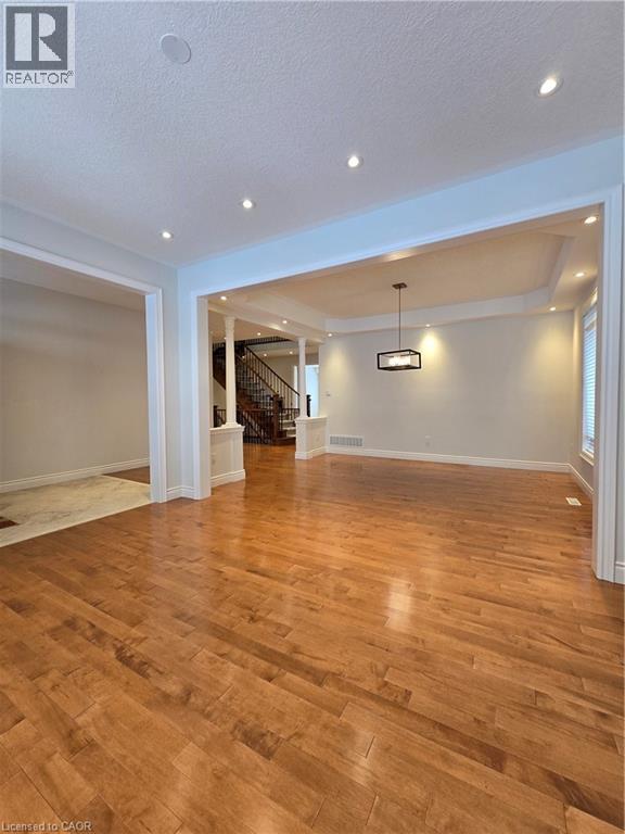 Unfurnished living room with light wood-style floors, stairs, a textured ceiling, and recessed lighting - 93 Tremaine Drive, Kitchener, ON - Indoor Photo Showing Other Room