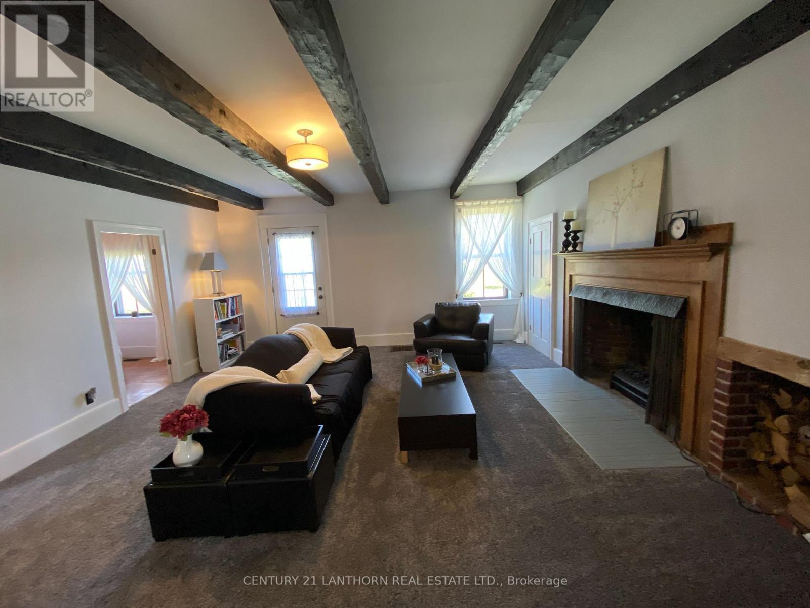 Original beamed ceilings throughout main level - 644 County 10 Road, Prince Edward County (Hallowell Ward), ON - Indoor Photo Showing Living Room With Fireplace