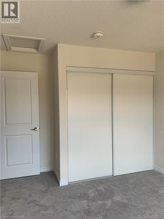 Unfurnished bedroom with carpet flooring, a textured ceiling, a closet, and attic access - 49 Eberhardt Drive, Wasaga Beach, ON - Indoor Photo Showing Other Room