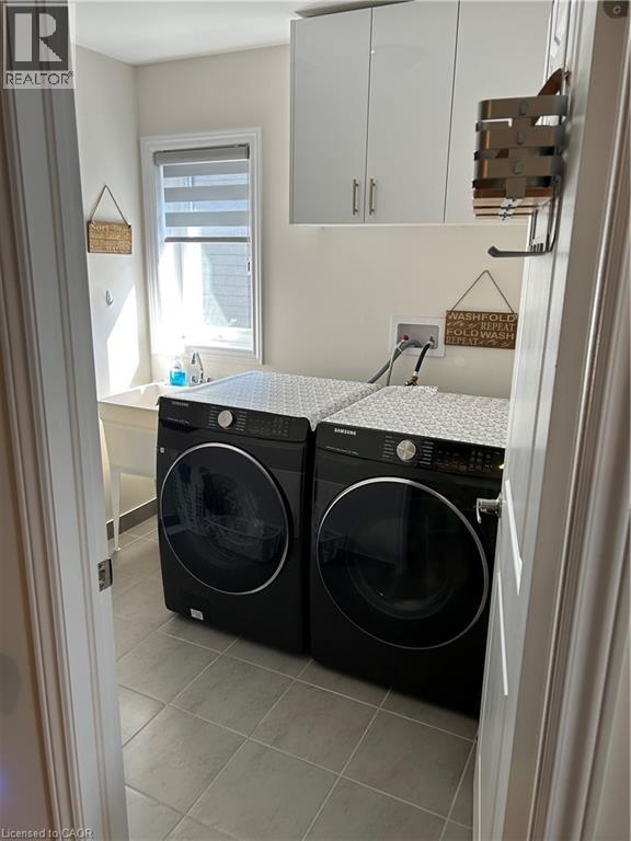Washroom with light tile patterned flooring, cabinet space, and washing machine and clothes dryer - 49 Eberhardt Drive, Wasaga Beach, ON - Indoor Photo Showing Laundry Room