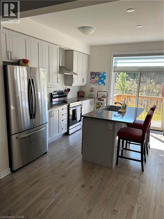 Kitchen with appliances with stainless steel finishes, exhaust hood, a kitchen bar, a kitchen island, and dark countertops - 49 Eberhardt Drive, Wasaga Beach, ON - Indoor Photo Showing Kitchen