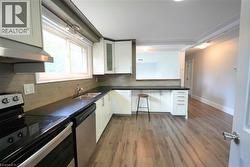 Kitchen with stainless steel appliances, under cabinet range hood, and white cabinets -