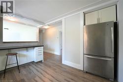 Kitchen featuring white cabinetry, freestanding refrigerator, dark countertops, dark wood-style floors, and a kitchen breakfast bar -