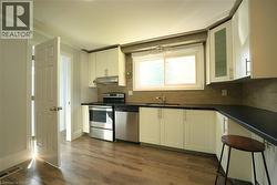 Kitchen featuring white cabinetry, appliances with stainless steel finishes, dark wood-style floors, decorative backsplash, and crown molding -
