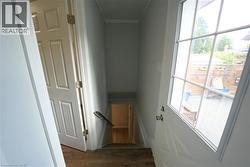 Stairway featuring wood finished floors and ornamental molding -