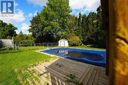 View of pool with a wooden deck, a storage unit, and a fenced backyard -