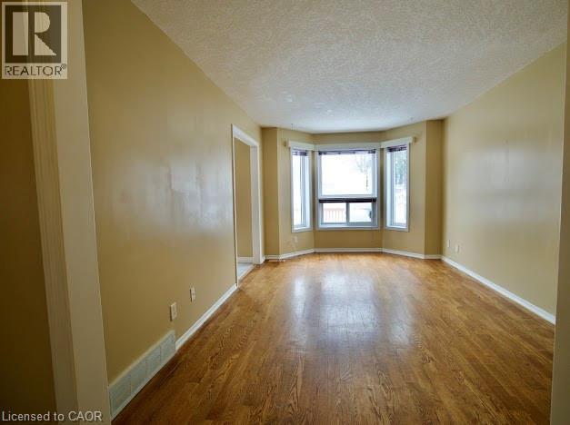 Unfurnished room with a textured ceiling and wood finished floors - 109 Beechmanor Crescent, Kitchener, ON - Indoor Photo Showing Other Room