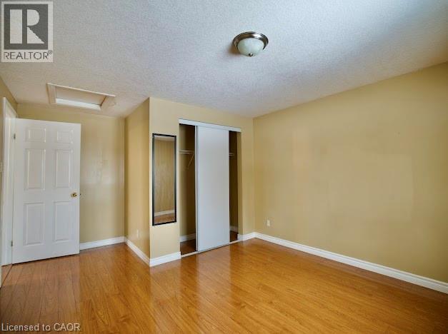Unfurnished bedroom featuring attic access, a textured ceiling, a closet, and light wood-style flooring - 109 Beechmanor Crescent, Kitchener, ON - Indoor Photo Showing Other Room