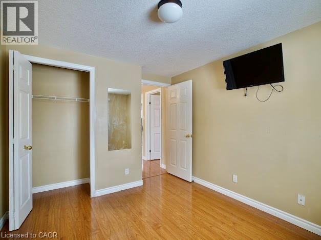 Unfurnished bedroom with a textured ceiling, wood finished floors, and a closet - 109 Beechmanor Crescent, Kitchener, ON - Indoor Photo Showing Other Room