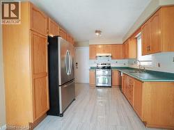 Kitchen featuring appliances with stainless steel finishes, decorative backsplash, light brown cabinetry, and under cabinet range hood -