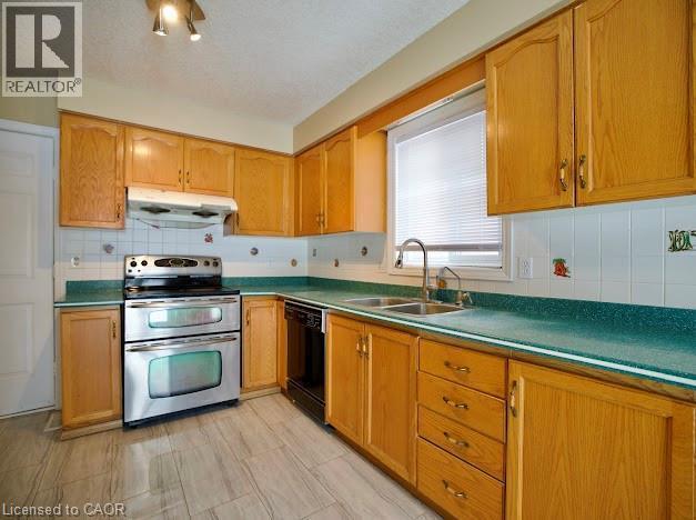Kitchen with range with two ovens, decorative backsplash, black dishwasher, and under cabinet range hood - 109 Beechmanor Crescent, Kitchener, ON - Indoor Photo Showing Kitchen With Double Sink