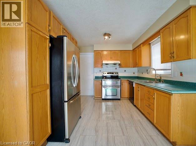Kitchen featuring appliances with stainless steel finishes, decorative backsplash, a textured ceiling, and under cabinet range hood - 109 Beechmanor Crescent, Kitchener, ON - Indoor Photo Showing Kitchen