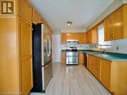 Kitchen featuring appliances with stainless steel finishes, decorative backsplash, a textured ceiling, and under cabinet range hood -
