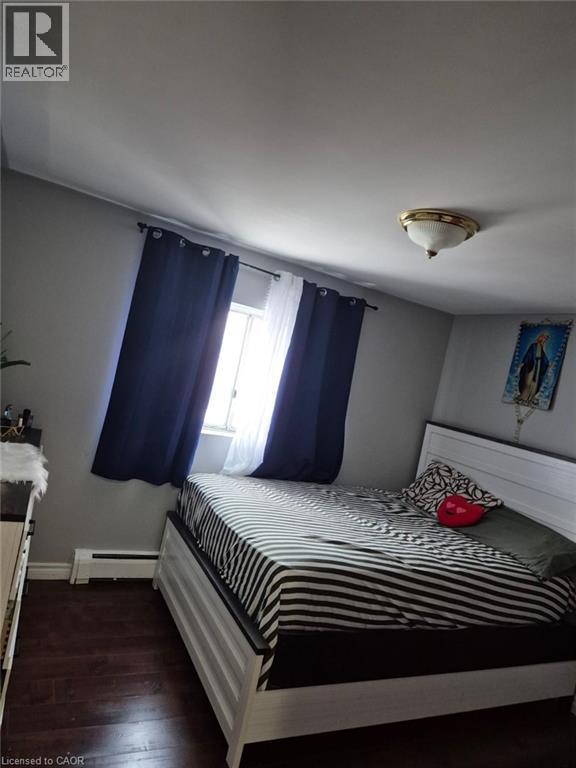 Bedroom featuring dark wood finished floors and a baseboard heating unit - 76 Brybeck Crescent Unit# 204, Kitchener, ON - Indoor Photo Showing Bedroom
