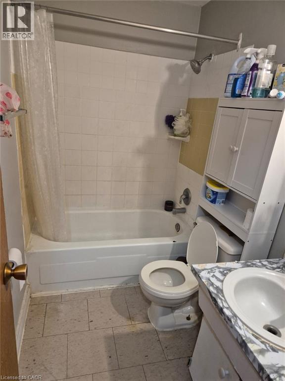 Full bath with shower / bath combo with shower curtain, vanity, and light tile patterned floors - 76 Brybeck Crescent Unit# 204, Kitchener, ON - Indoor Photo Showing Bathroom