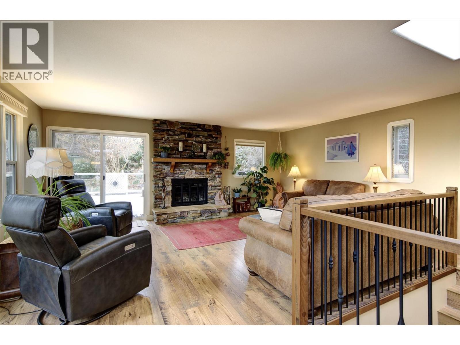 Access from the living room to the patio - 391 Braeloch Road, Kelowna, BC - Indoor Photo Showing Living Room With Fireplace