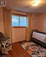 Bedroom with a crib and dark wood-style flooring -