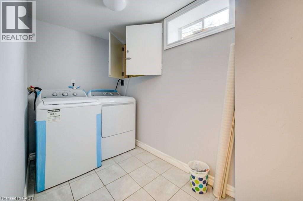 Laundry area with cabinet space, independent washer and dryer, and light tile patterned floors - 33 Garland Crescent, London, ON - Indoor Photo Showing Laundry Room