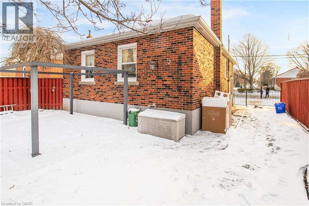 View of snow covered exterior with brick siding and a chimney - 773 Queensdale Avenue E, Hamilton, ON - Outdoor