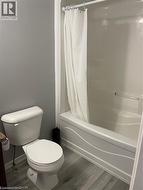 Bathroom with shower / tub combo with curtain and wood finished floors -