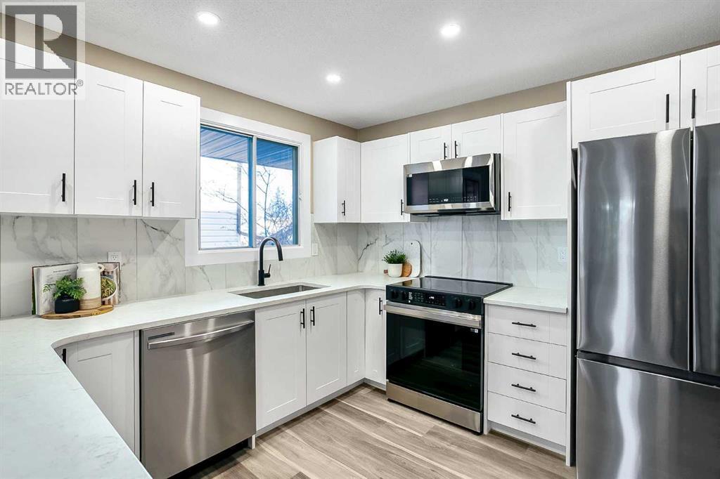Kitchen has been updated with timeless white shaker cabinets, brand new stainless steel appliances & quartz counters - 467 Berkley Crescent Nw, Calgary, AB - Indoor Photo Showing Kitchen With Upgraded Kitchen