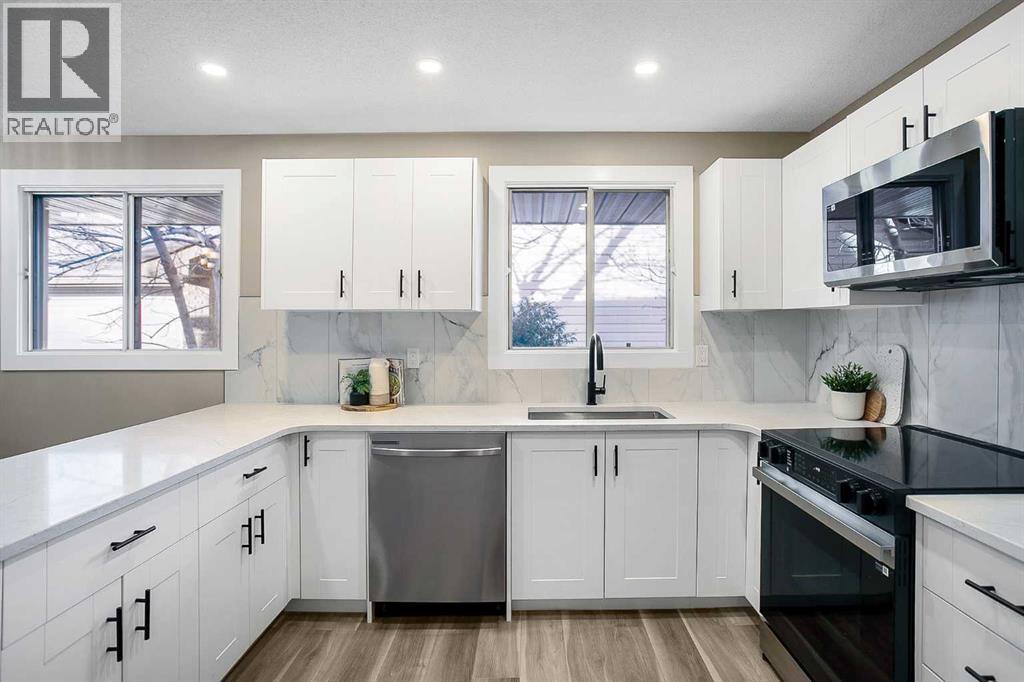 Kitchen has been updated with timeless white shaker cabinets, brand new stainless steel appliances & quartz counters - 467 Berkley Crescent Nw, Calgary, AB - Indoor Photo Showing Kitchen With Upgraded Kitchen