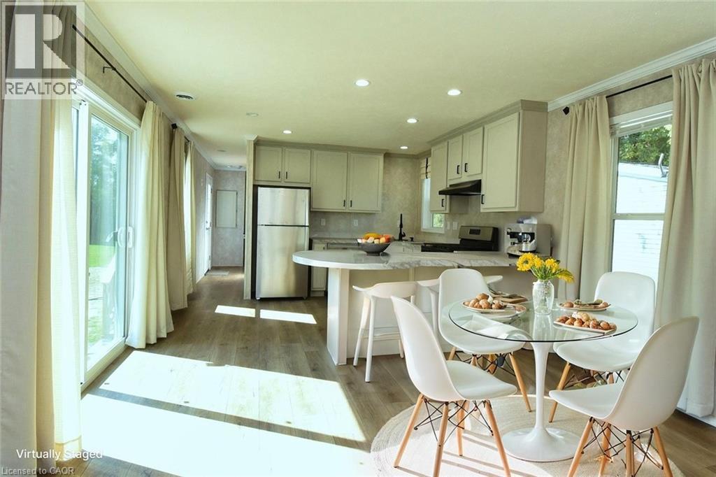 Kitchen featuring a peninsula, freestanding refrigerator, electric stove, light wood finished floors, and a breakfast bar area - 1085 Concession 10 Road W Unit# 23, Flamborough, ON - Indoor Photo Showing Dining Room