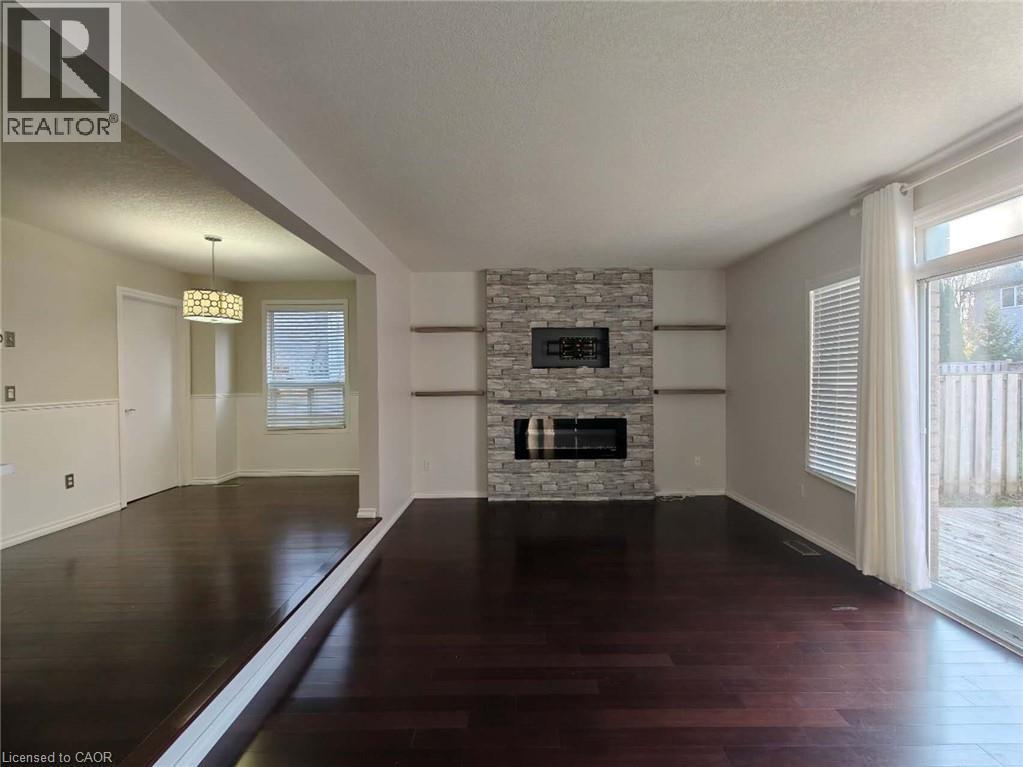 Unfurnished living room featuring a textured ceiling, dark wood-style floors, and a fireplace - 563 Dansbury Drive, Waterloo, ON