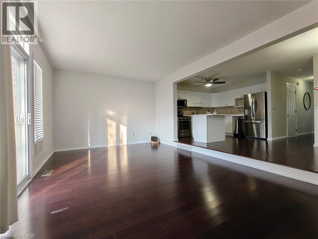 Unfurnished living room featuring dark wood-style flooring, ceiling fan, and a textured ceiling - 563 Dansbury Drive, Waterloo, ON