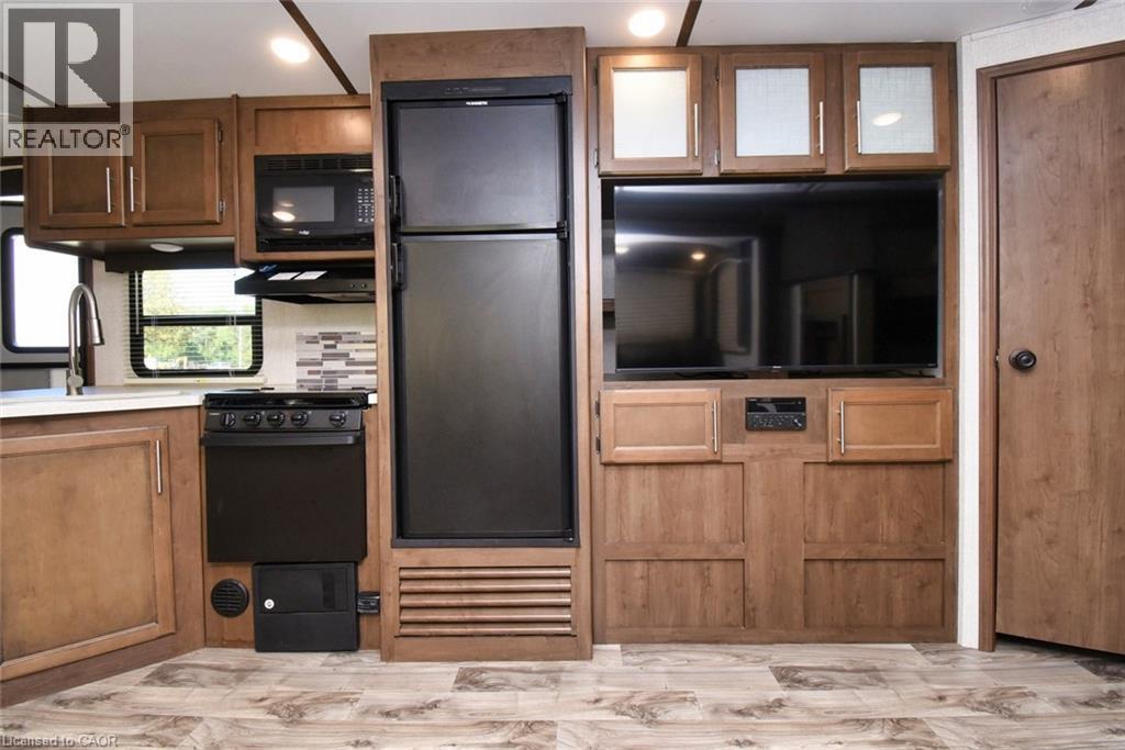 Kitchen featuring black appliances, ventilation hood, light wood-style floors, and brown cabinetry - 1085 10Th Concession Road W Unit# 29, Flamborough, ON - Indoor Photo Showing Kitchen