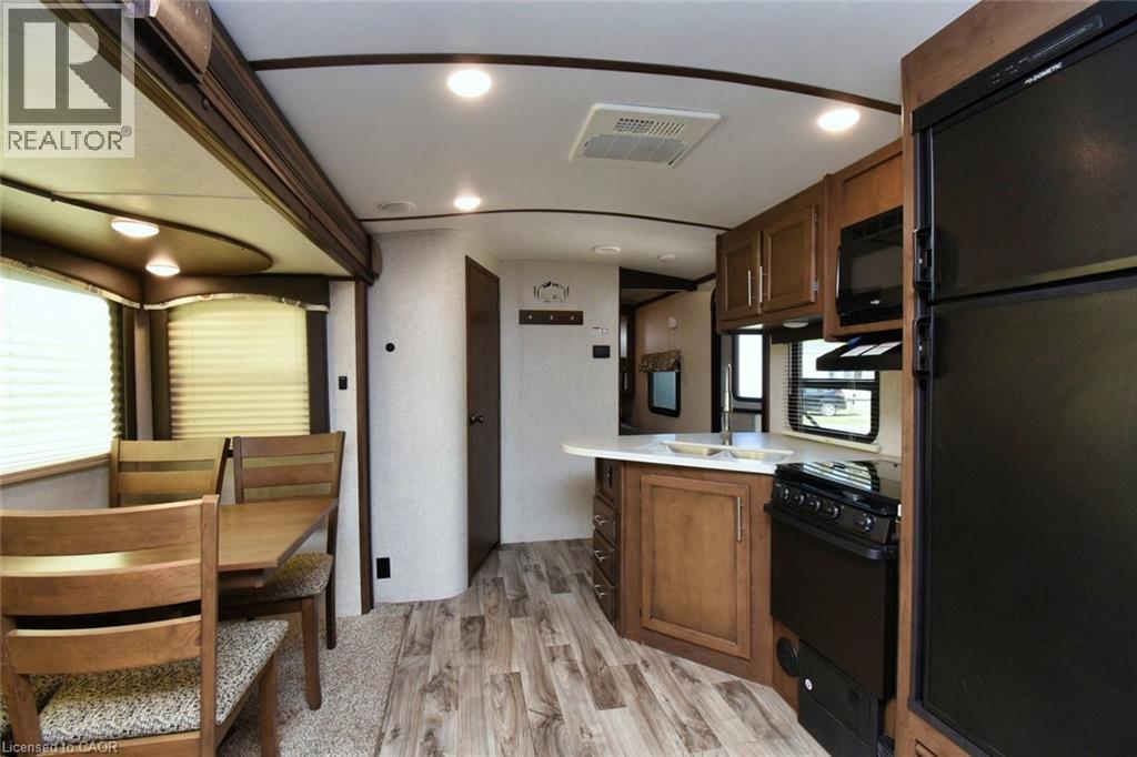 Kitchen with black appliances, light countertops, a peninsula, light wood-style floors, and brown cabinetry - 1085 10Th Concession Road W Unit# 29, Flamborough, ON - Indoor