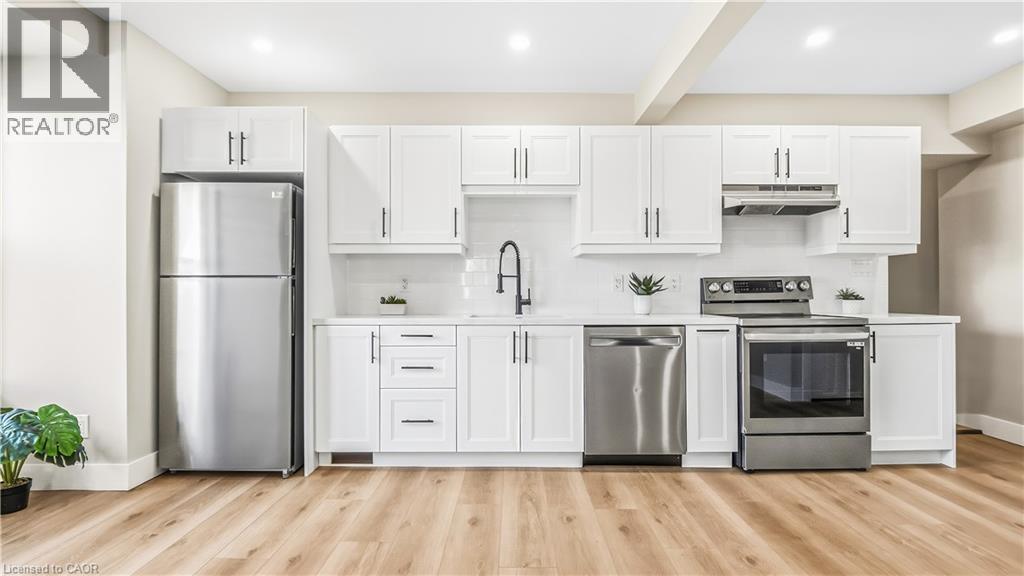 Kitchen with white cabinets, appliances with stainless steel finishes, tasteful backsplash, light wood finished floors, and beam ceiling - 491 Upper Wentworth Street, Hamilton, ON - Indoor Photo Showing Kitchen