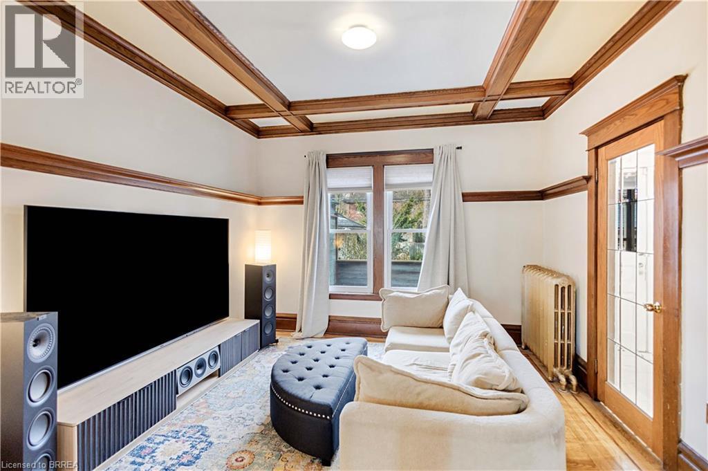 Living room featuring beam ceiling, coffered ceiling, radiator heating unit, wood finished floors, and crown molding - 134 Sherman Avenue S, Hamilton, ON - Indoor Photo Showing Living Room