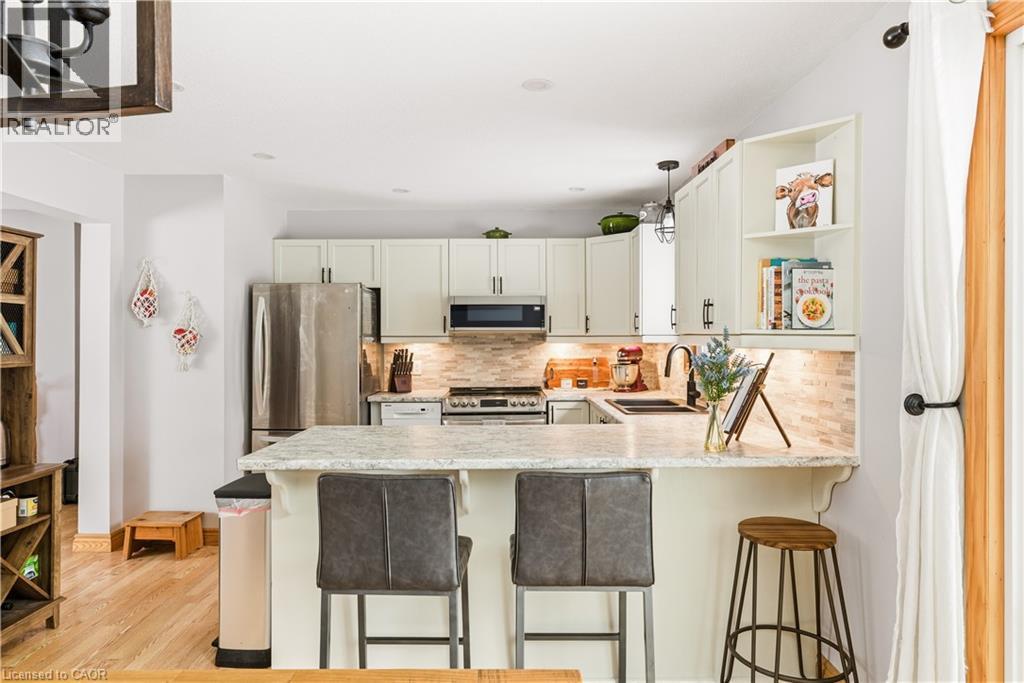 Kitchen with decorative light fixtures, appliances with stainless steel finishes, backsplash, and a breakfast bar area - 230 Saugeen Street, Grey Highlands, ON - Indoor Photo Showing Kitchen With Double Sink With Upgraded Kitchen