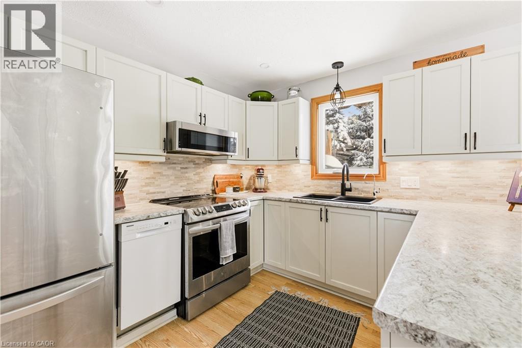 Kitchen featuring appliances with stainless steel finishes, decorative light fixtures, white cabinetry, light wood-type flooring, and tasteful backsplash - 230 Saugeen Street, Grey Highlands, ON - Indoor Photo Showing Kitchen With Upgraded Kitchen