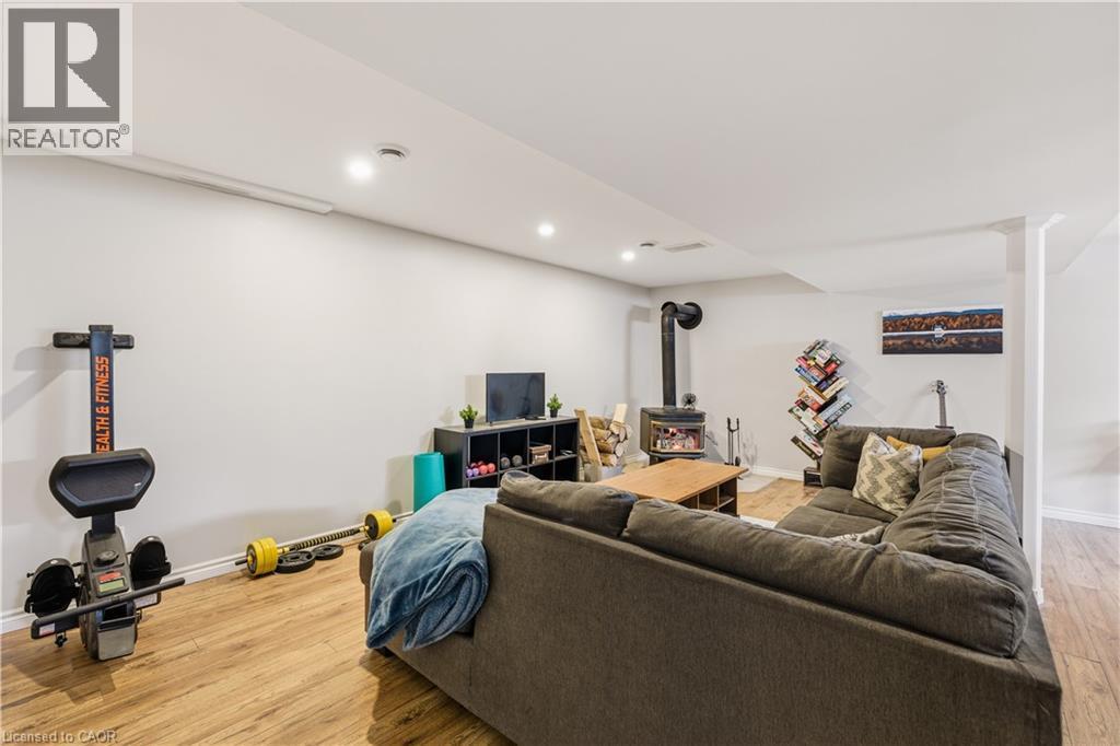 Living area featuring a wood stove, light wood-style flooring, and recessed lighting - 230 Saugeen Street, Grey Highlands, ON - Indoor Photo Showing Basement