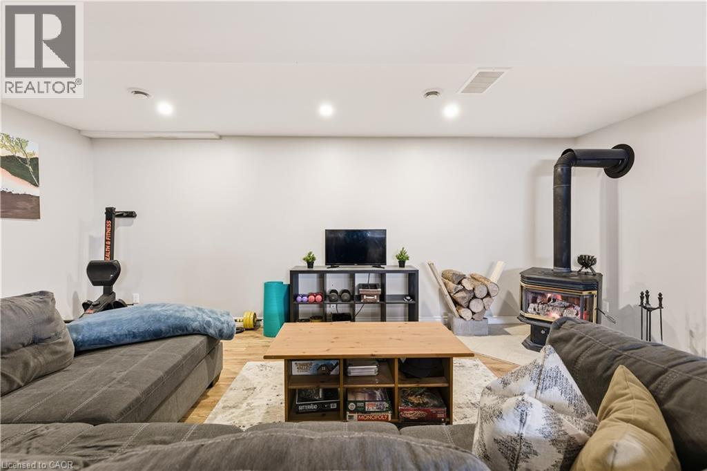 Living room with a wood stove, wood finished floors, and recessed lighting - 230 Saugeen Street, Grey Highlands, ON - Indoor Photo Showing Basement