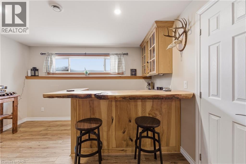 Bar area featuring light wood-style flooring and glass insert cabinets - 230 Saugeen Street, Grey Highlands, ON - Indoor