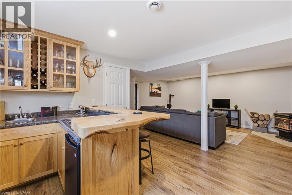 Kitchen with a wood stove, a peninsula, glass insert cabinets, a kitchen bar, and light wood-style floors - 230 Saugeen Street, Grey Highlands, ON - Indoor Photo Showing Kitchen