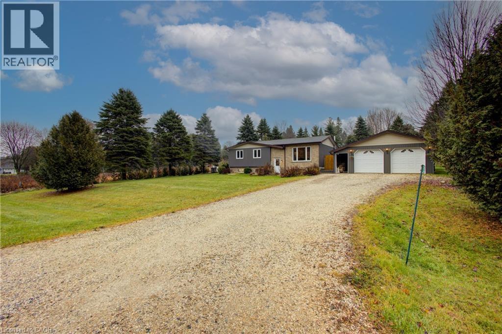 View of front of property featuring a front lawn, a garage, and an outdoor structure - 230 Saugeen Street, Grey Highlands, ON - Outdoor