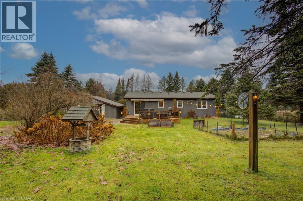 Rear view of house with a wooden deck, a yard, a vegetable garden, and view of scattered trees - 230 Saugeen Street, Grey Highlands, ON - Outdoor With Deck Patio Veranda