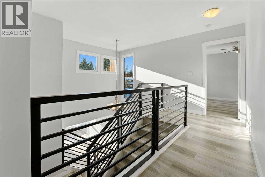 A bright stairwell with a modern black metal railing and additional windows connects the main floor and second level - 4 Pardue Close, Red Deer, AB - Indoor Photo Showing Other Room
