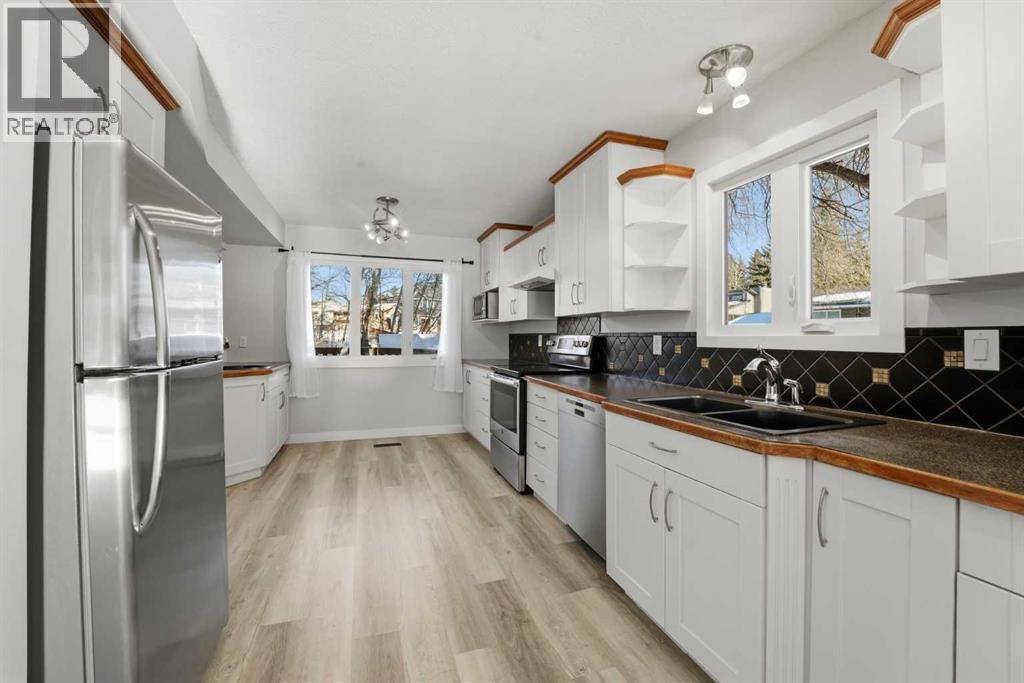 The galley-style kitchen showcases stylish cabinetry, a pantry, two sinks, and upgraded stainless steel appliances - 4 Pardue Close, Red Deer, AB - Indoor Photo Showing Kitchen With Double Sink