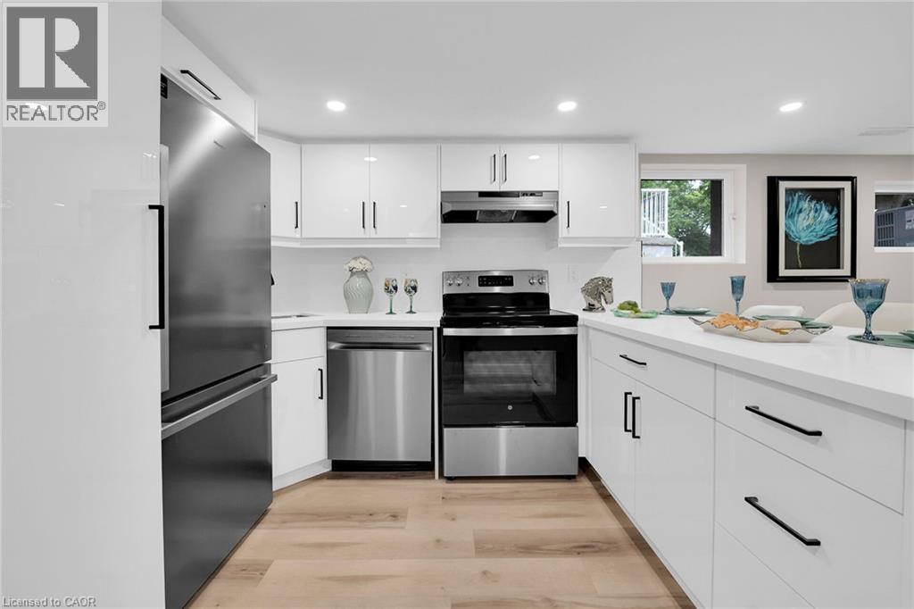Kitchen featuring appliances with stainless steel finishes, white cabinetry, light wood-style flooring, recessed lighting, and under cabinet range hood - 174 East 34Th Street, Hamilton, ON - Indoor Photo Showing Kitchen
