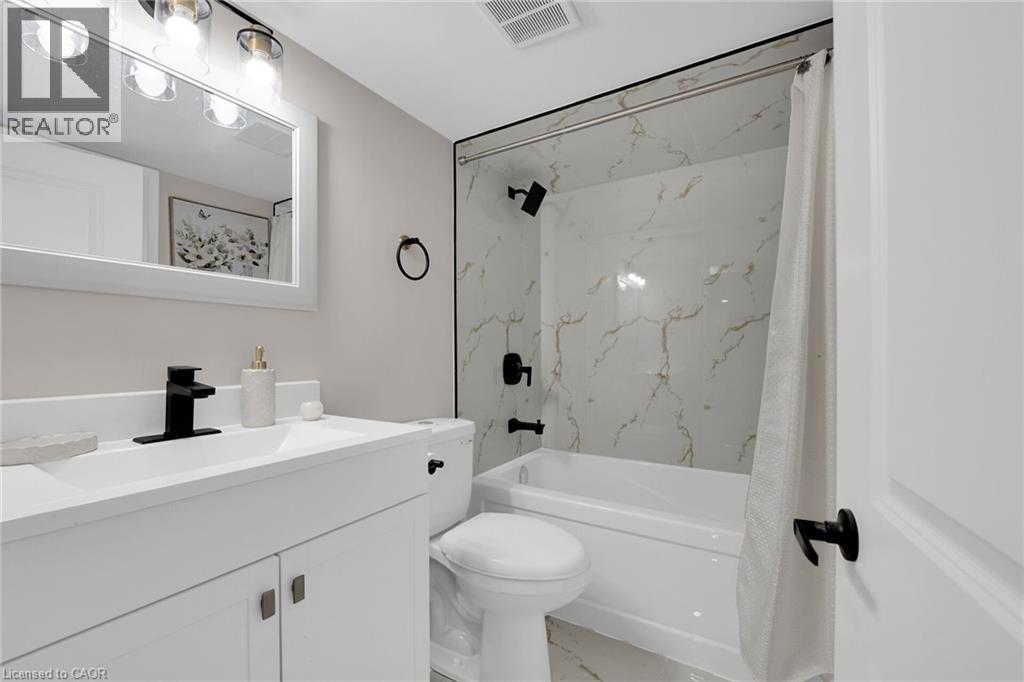 Bathroom with light marble finish floors, vanity, and shower / bath combination with curtain - 174 East 34Th Street, Hamilton, ON - Indoor Photo Showing Bathroom