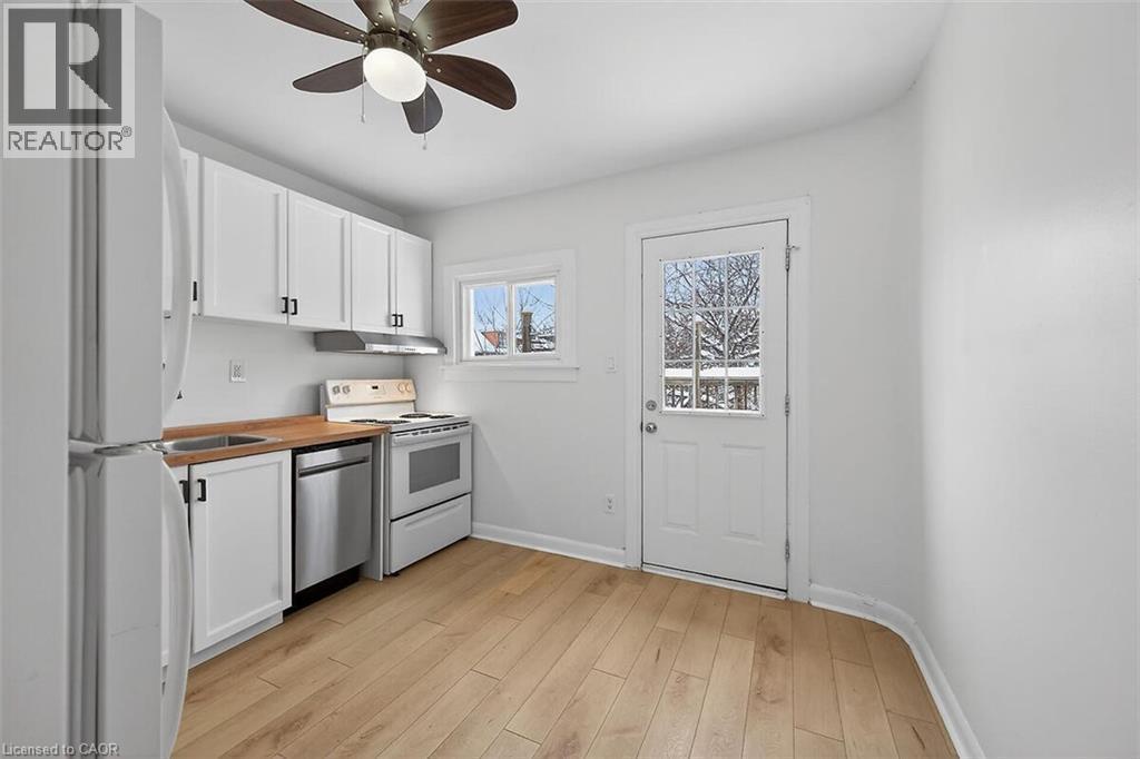 Kitchen featuring white cabinetry, appliances, light wood-style floors, wooden counters, and a ceiling fan, door to rear balcony. - 77 Barton Street E Unit# 2, Hamilton, ON - Indoor Photo Showing Kitchen